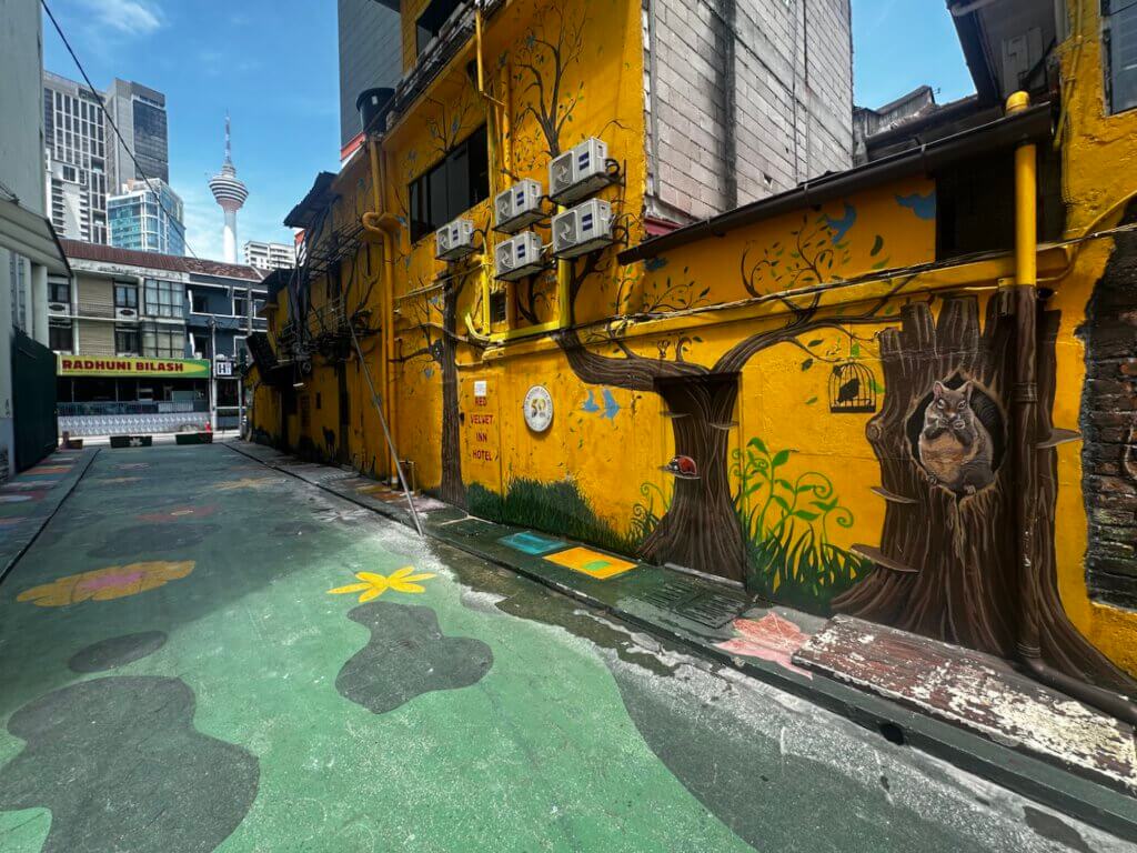 Bunte Street-Art-Gasse mit Wandmalereien und Blick auf den KL Tower in Kuala Lumpur, Malaysia