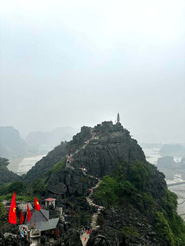 Aussichtspunkt Mua Cave bei Tam Coc in Vietnam mit Karstbergen, Treppenaufstieg und Pagode im Nebel