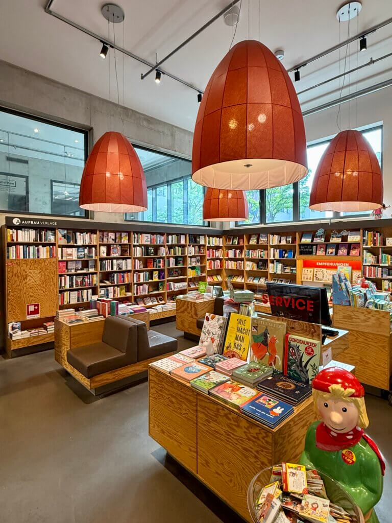 Innenansicht der Buchhandlung Moritzplatz im Aufbau Haus mit großen Lampen, Bücherinseln und gemütlichen Sitzgelegenheiten